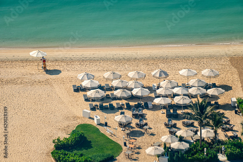 beach with tourists enjoying the sun and sea, sitting under umbrellas aerial top view from above timelapse.