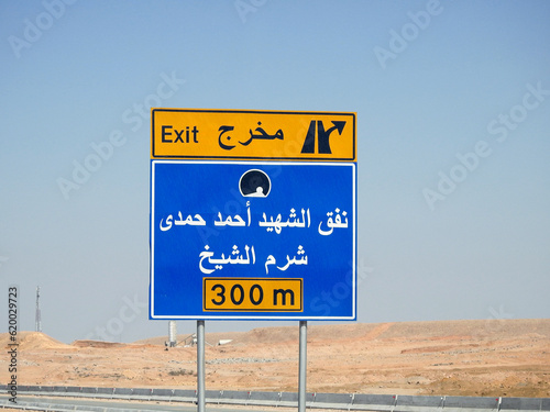 Translation of Arabic Text on the side traffic sign directional board (Exit Of Martyr Ahmed Hamdy Tunnel, Sharm El Sheikh city 300 Meters ahead) Ahmad Hamdi tunnel and Sharm Al Sheikh city direction photo
