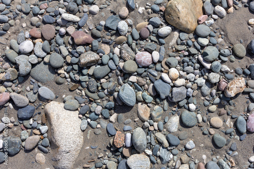 the rocky bottom of the river on the shallows during low water, warmed by the sun's rays - small pebbles.