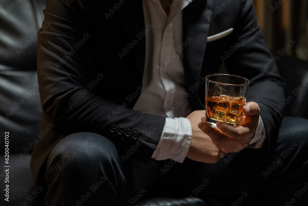 Businessman sitting Holding a Glass of Whiskey Drink Whiskey in the liquor store room