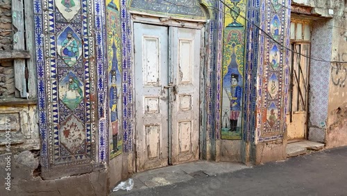 Walking tour in walkway in Rasht old city town in front of an Persian ancient colorful historical workshop landmark gate with blue tiles wall of love fame in down town in a farmer local people market photo