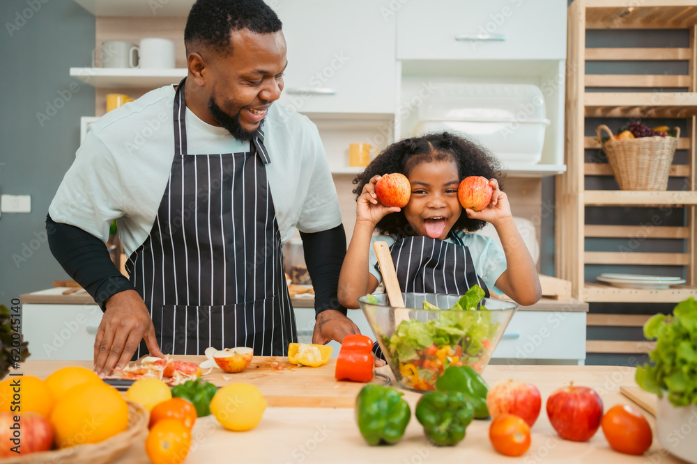black people family in cook time, people who father and mother with child or girl daughter having smile and happy to cooking a food in kitchen at home, fun making vegetables salad for healthy together
