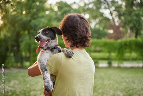 Outdoor portrait of boy with his adopted dog. Friendship of teenager with pet, boy walking in summer meadow, scenic sunset landscapes background. High quality photo