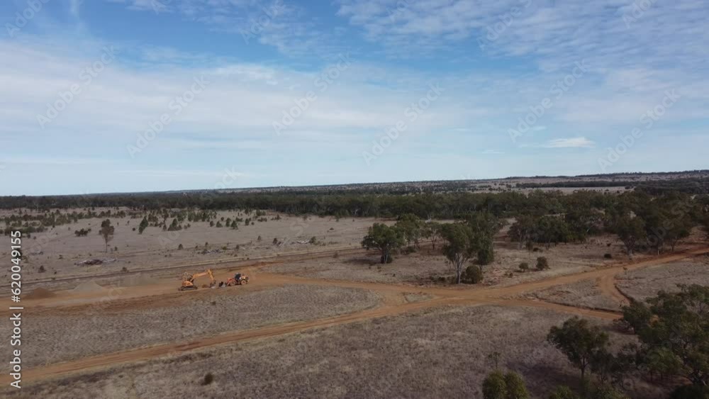 Drone flying towards heavy machinery in a desert style landscape. Dirt roads visible Drone flying towards heavy machinery in a desert style landscape. Dirt roads visible