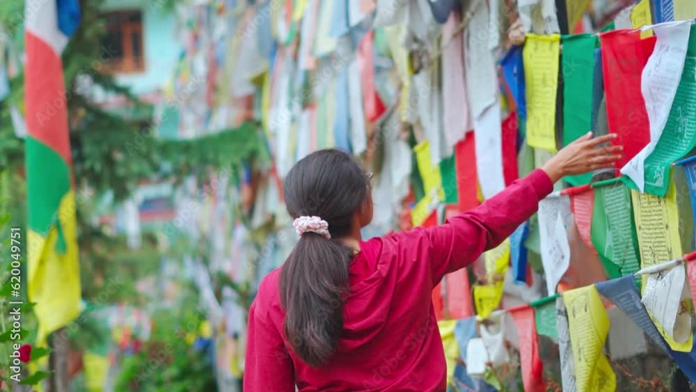 Tourist Indian girl touching Buddhist prayer flags in Himalayan