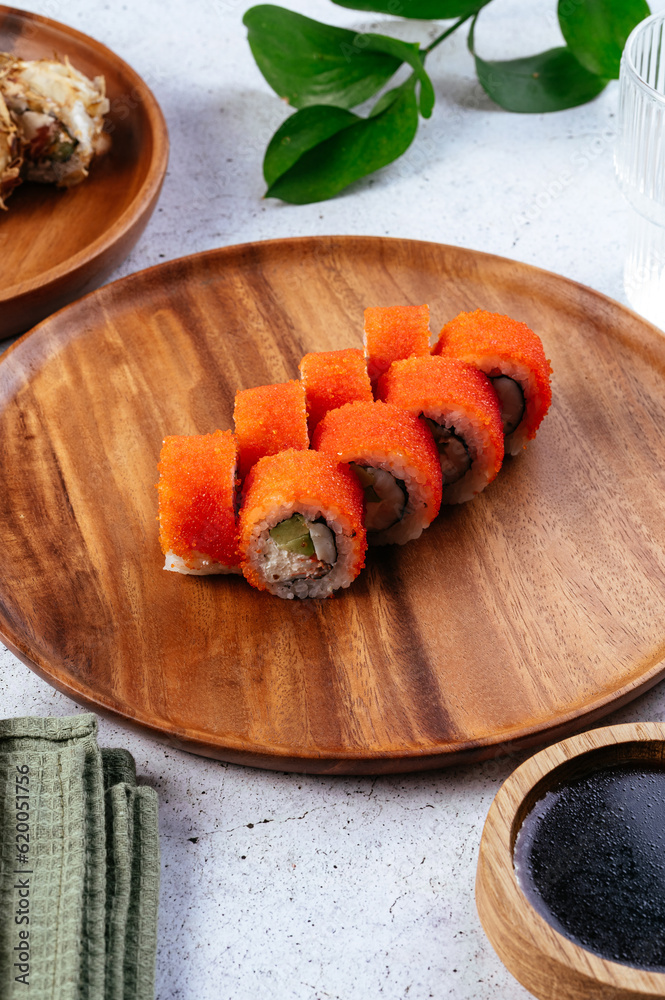 Sushi and soy sauce in a bowl and wooden chopsticks on a gray wo Sushi and soy sauce in a bowl and wooden chopsticks on a gray wo