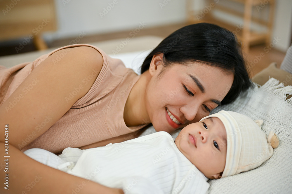 Beautiful asian mom lay down with her baby, comforting her son on bed. Beautiful asian mom lay down with her baby, comforting her son on bed.