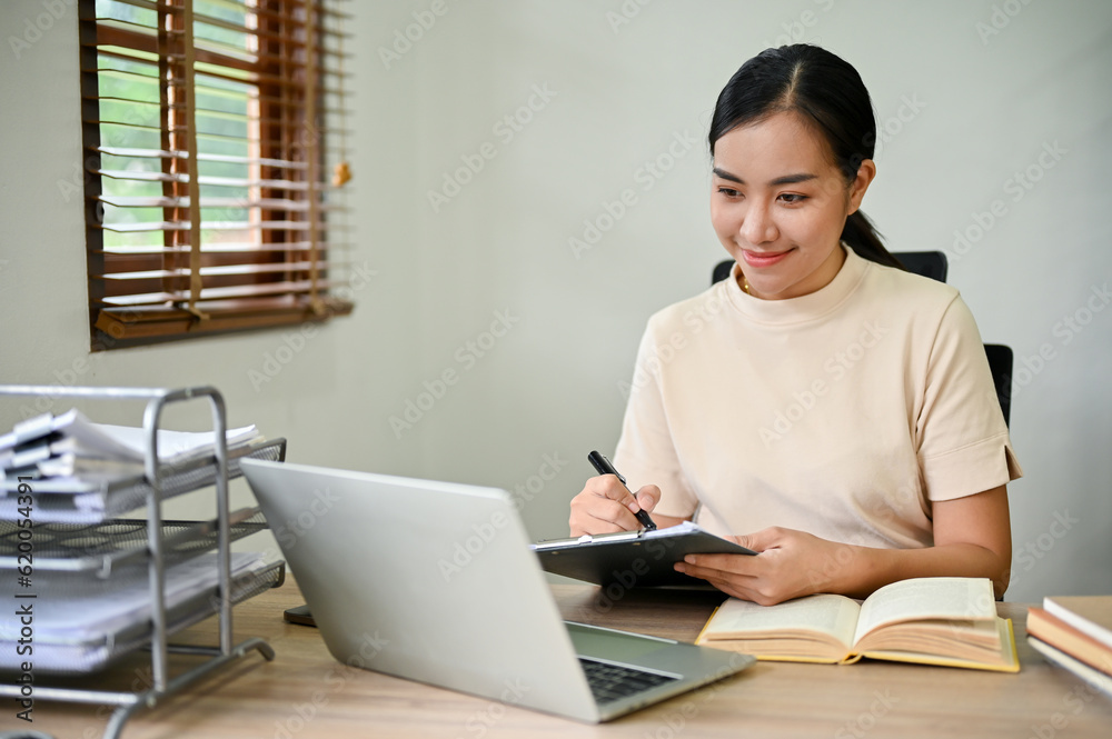 Beautiful Asian woman working with digital tablet in her desk, working from home Beautiful Asian woman working with digital tablet in her desk, working from home