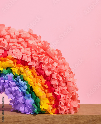 Colorful bright pinata rainbow stands on a wooden surface. Festive and colorful mood.
