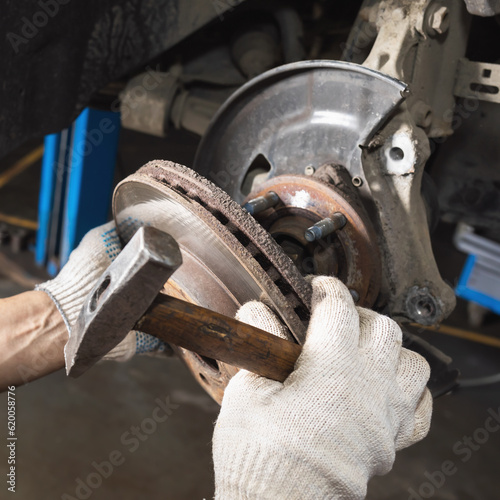 Auto mechanic removes an old rusty brake disc to replace it with a new one