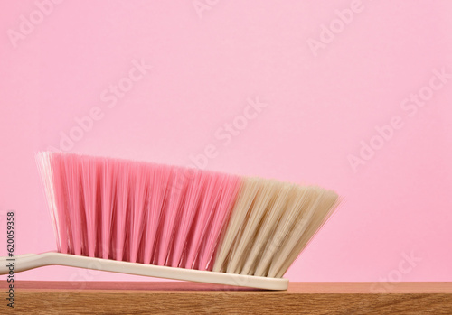Cleaning supplies on a wooden table. Brush with thick natural bristles in different colors. Copy space for text. © Dima