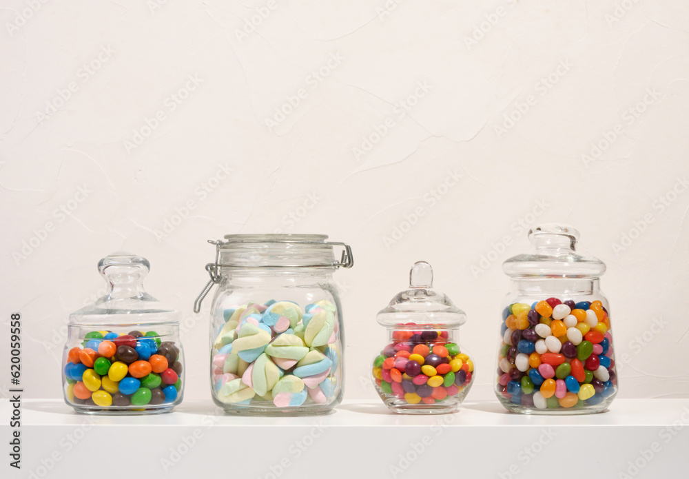 Soft fresh marshmallows, delicious sweet candies in glass jars on the table. Composition with different yummy candies. Soft fresh marshmallows, delicious sweet candies in glass jars on the table. Composition with different yummy candies.