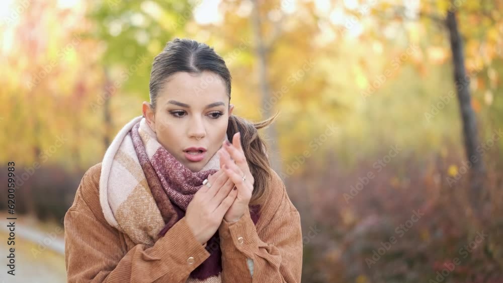 Caucasian young woman rubbing her hands, coughing and blowing nose into tissue during autumn. Cold weather. Flu. Caucasian young woman rubbing her hands, coughing and blowing nose into tissue during autumn. Cold weather. Flu.