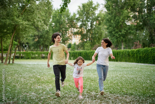 Smiling Family Running Across Summer Field Together. Mother Daughter son, hands together High quality photo