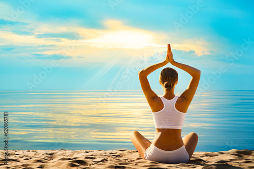 Yoga Meditation by Sea. Woman Rear view meditating at Sunset Beach Outdoors. Women Silhouette in Lotus Namaste position over Sunshine Blue Sky background