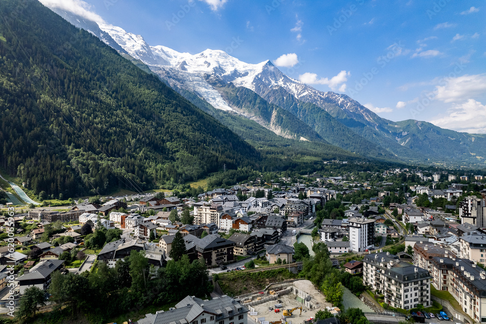 Aerial of Chamonix village at the feet of the Mont Blanc Massive mountain range with eternal snow tops in the background during summer. Tourist destination and outdoor winter sports  ski resort.