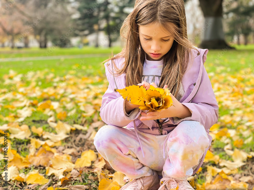 Cute little girl holding yellow leaves in her hands. Winter in Australia. Flagstaff gardens, Melbourne, Australia. Cute little girl holding yellow leaves in her hands. Winter in Australia. Flagstaff gardens, Melbourne, Australia.