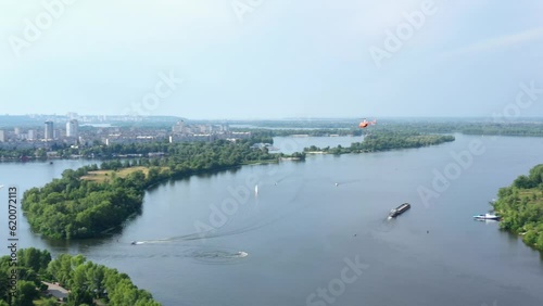 Orange helicopter flies over the Dnieper river in Kiev. View from the drone. photo