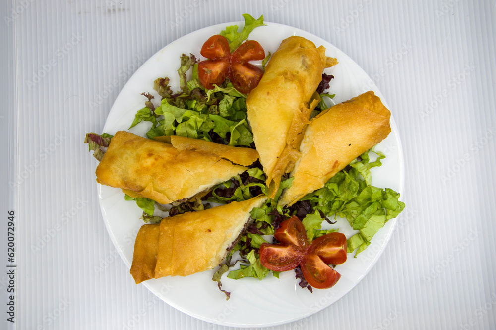 Turkish pastry made with pastrami and yufka served with tomato and lettuce Turkish pastry made with pastrami and yufka served with tomato and lettuce