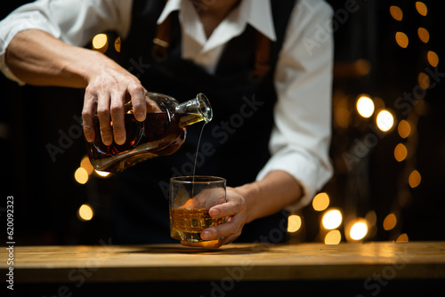 Bartender pours whiskey to customer in tavern