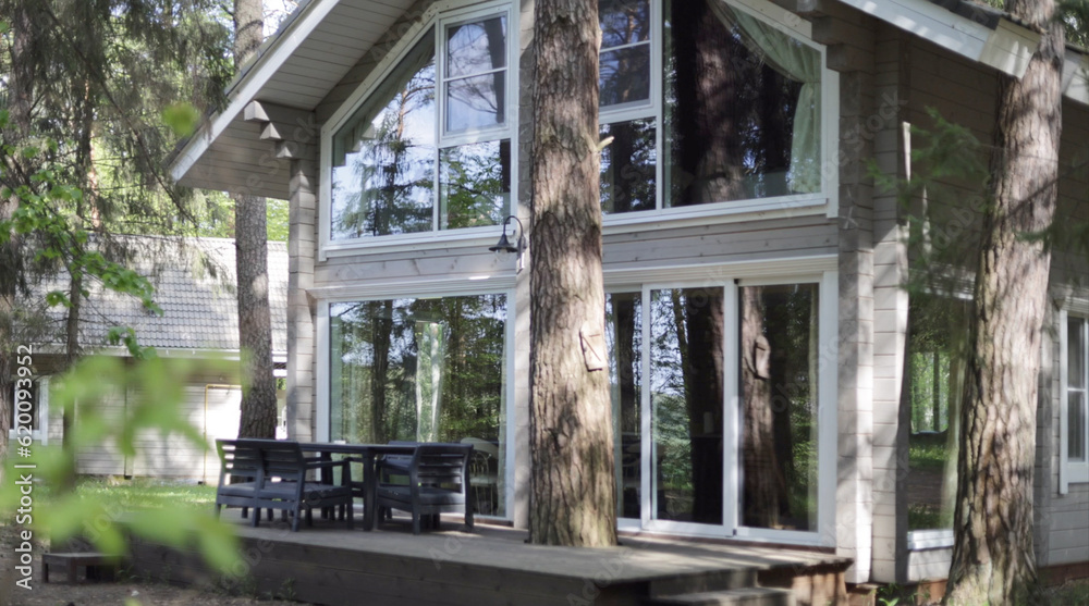 Country house made of wood with large panoramic windows in the forest in the summer in the pines