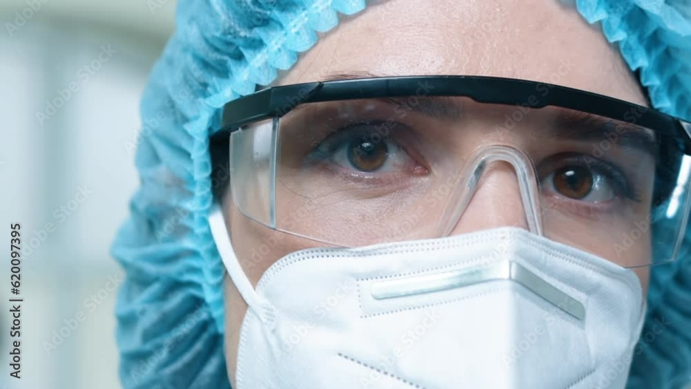Portrait of woman chemist posing at laboratory. Female laboratory worker in medical hat. Scientist dressed up in face mask and protective glasses. Close up of woman head in laboratory. Portrait of woman chemist posing at laboratory. Female laboratory worker in medical hat. Scientist dressed up in face mask and protective glasses. Close up of woman head in laboratory.