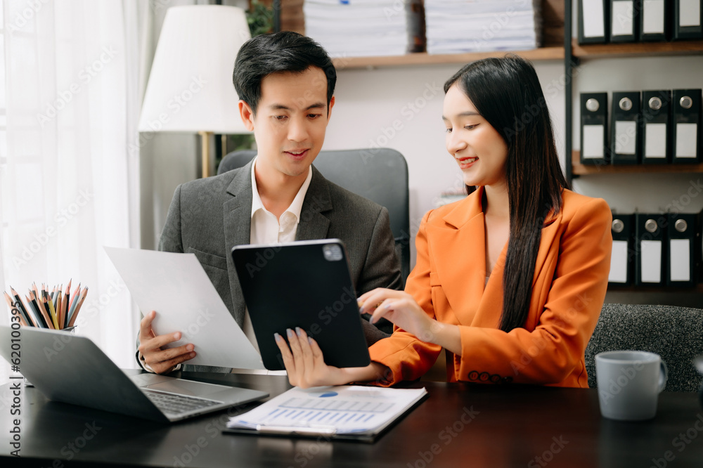 Two Asian businesswoman discuss investment project working and planning strategy with tablet laptop computer in office. Two Asian businesswoman discuss investment project working and planning strategy with tablet laptop computer in office.
