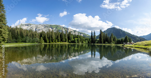 Panorama of Gold miners lake or Lac des Mines d'Or with still water reflecting the spectacular nature of French Alps mountain range during summer. Melt water reservoir.