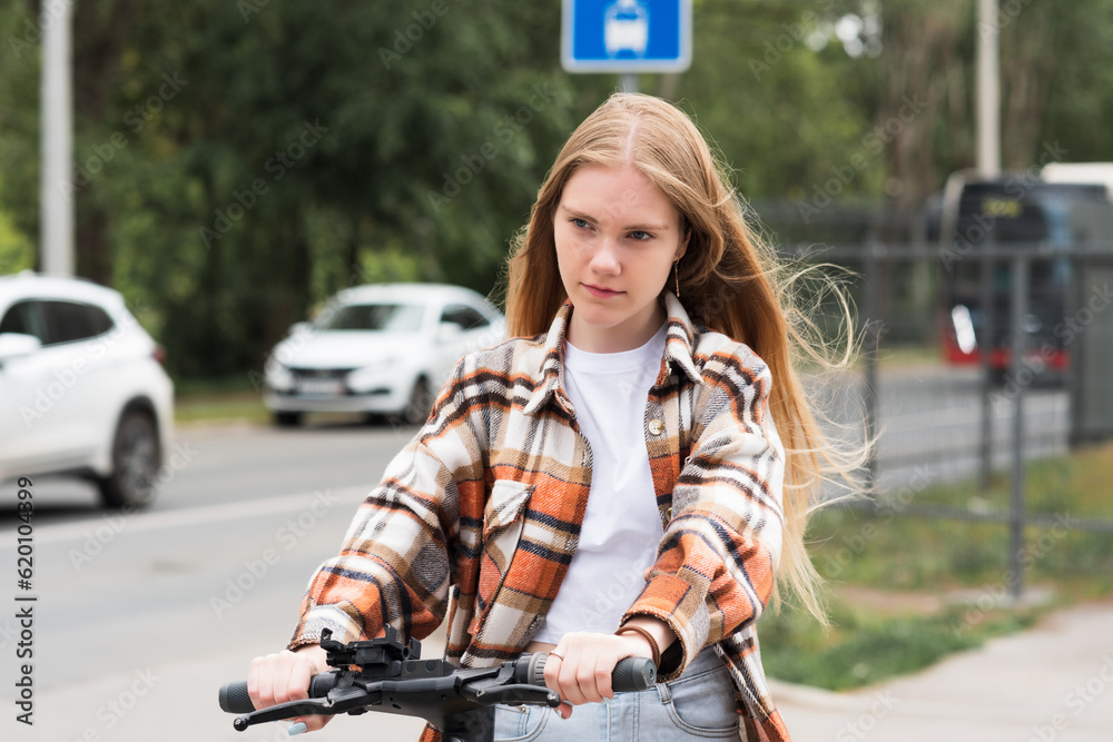 young woman on an electric scooter rides down the street