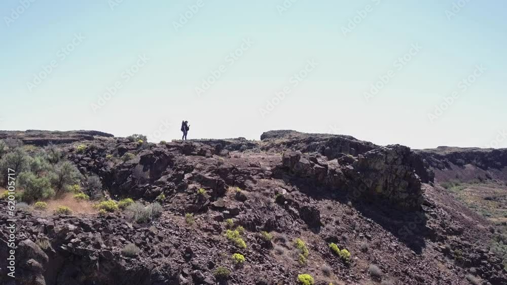 Hiker with backpack walks near canyon rim in Channeled Scablands, WA Hiker with backpack walks near canyon rim in Channeled Scablands, WA