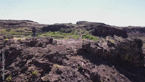 Female hiker takes panoramic photo of wild Scablands coulee waterfall photo