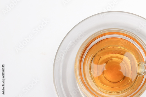 Hot tea in transparent glass cup saucer on white background