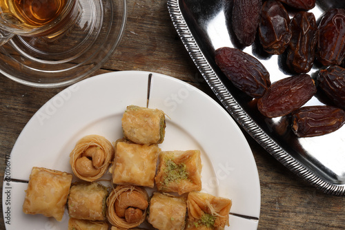 Layered stuffed pastry Baklava middle eastern sweet dessert dry ripe sweet date fruit tea in transparent glass cup saucer on rustic wooden background photo