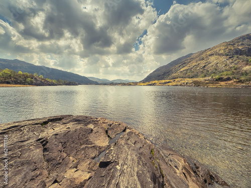 Rock, lake and mountain and dramatic sky. Beautiful nature scenery in county Kerry, Ireland. Irish stunning nature scene landscape. Travel and explore concept. Sightseeing and relaxing in nature area photo