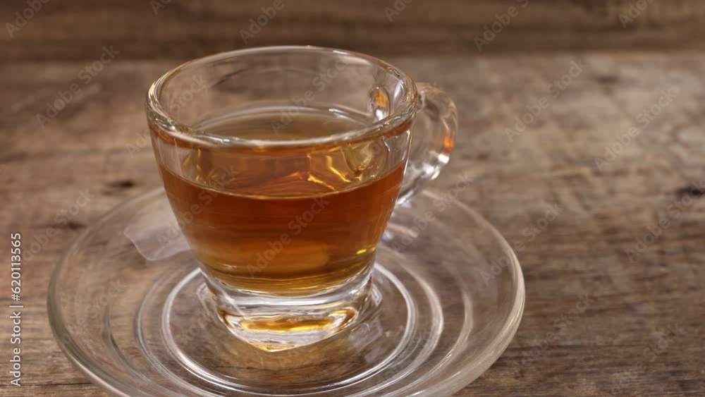 Hot tea in transparent glass cup saucer on rustic wood table background bring in keep put down pan rotate move Hot tea in transparent glass cup saucer on rustic wood table background bring in keep put down pan rotate move