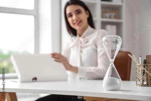 Hourglass on table of businesswoman in office. Time management concept