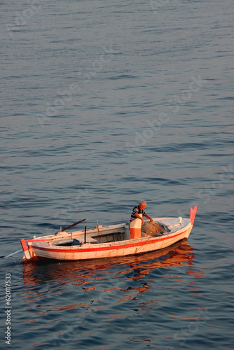 Beautiful sunset over the Adriatic Sea. Small old fashioned fishing boat at the sea. © jelena990