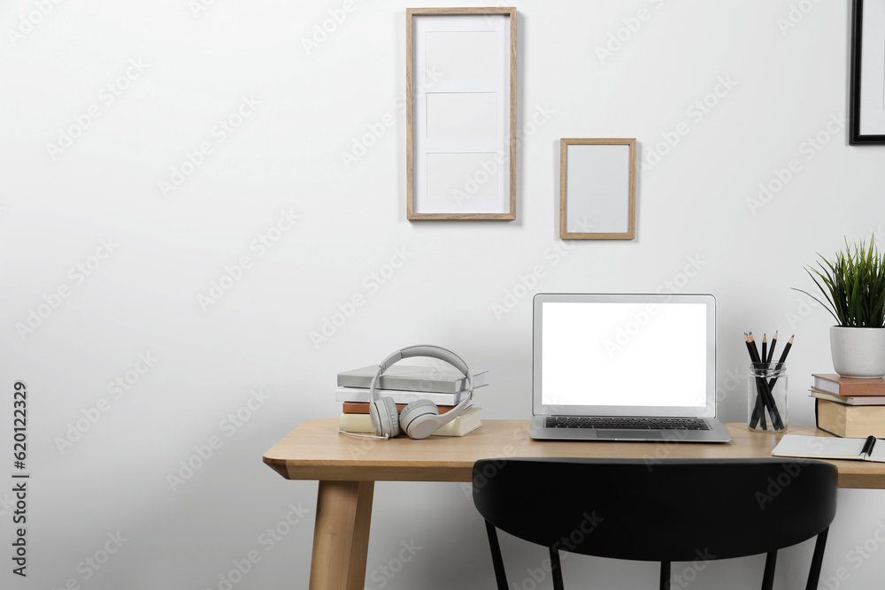 Cozy workspace with laptop and stationery on wooden desk at home Cozy workspace with laptop and stationery on wooden desk at home