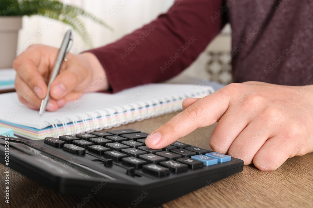 Fototapeta premium Man calculating pension at wooden table, closeup