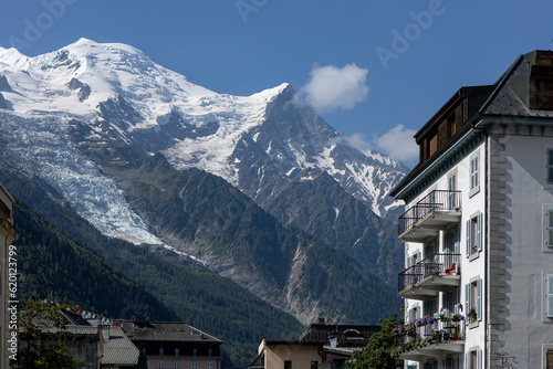 Eternal snow on the Mont Blanc massive rising above the buildings of ski village Chamonix in the French Alps against a clear blue sky.