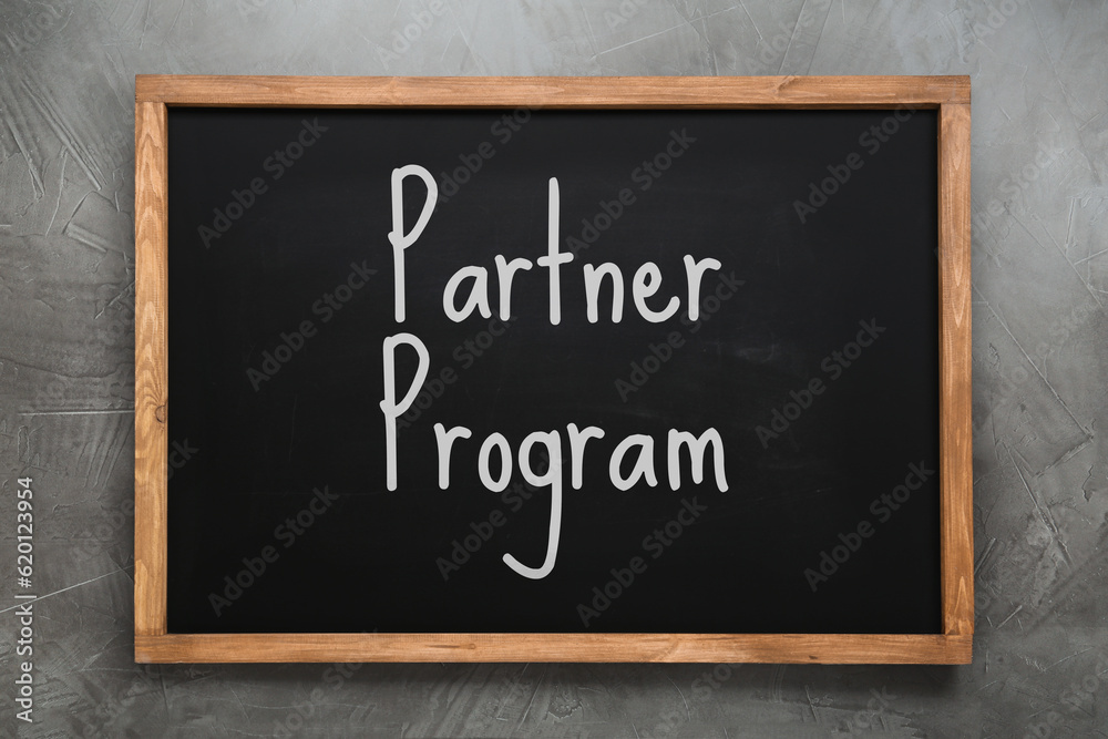 Obraz premium Black chalkboard with words Partner Program on grey wall