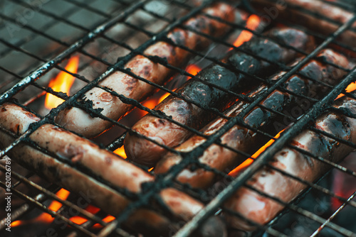 Milk sausages on a barbecue grill are roasted over a fire. Sausages in the flames of the fire outdoors. Yummy sausages