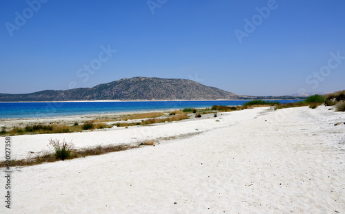 Fototapeta Naklejka Na Ścianę i Meble -  sandy beach with white sand, mountain, blue water and clear sky, copy space 