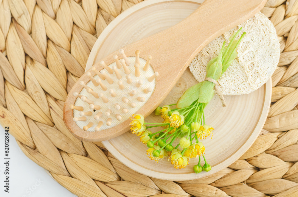 Wooden hairbrush and linden (tilia, basswood, lime tree) flowers. Natural hair care, homemade spa and beauty treatment recipe.