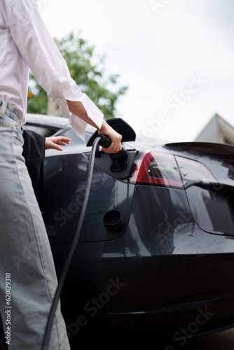 Electric car charging, Woman connecting a charging cable to a car. Green Energy concept