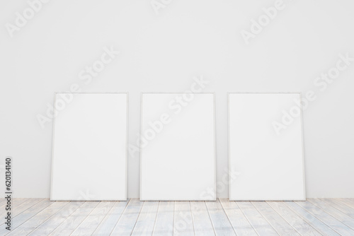 Three empty wooden frames for a photo or picture on the floor near a white wall. Models of paintings  posters  photographs. Design template for layout. 3D rendering.