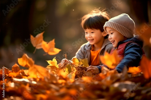 asian kids playing in autumn leaves on a sunny day