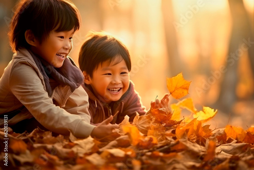 asian kids playing in autumn leaves on a sunny day