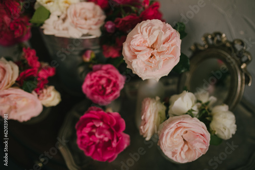 Still life with many different garden roses on a vintage table on grey background.