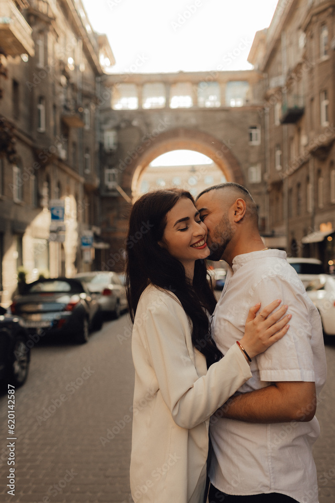 The couple walks around Kyiv. Old city. Love story. Walk around the city. A woman in a white suit. Guy in a t-shirt and jeans. Love and hugs. To cross the road. No focus blurred and noise effect The couple walks around Kyiv. Old city. Love story. Walk around the city. A woman in a white suit. Guy in a t-shirt and jeans. Love and hugs. To cross the road. No focus blurred and noise effect